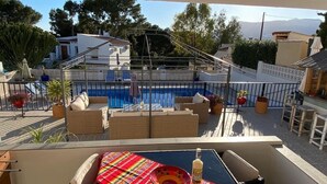 Ein Balkon mit Pool, Korbmöbeln und Topfpflanzen.