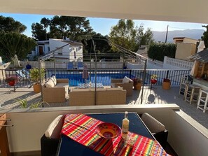 Ein Balkon mit Pool, Korbmöbeln und Topfpflanzen.
