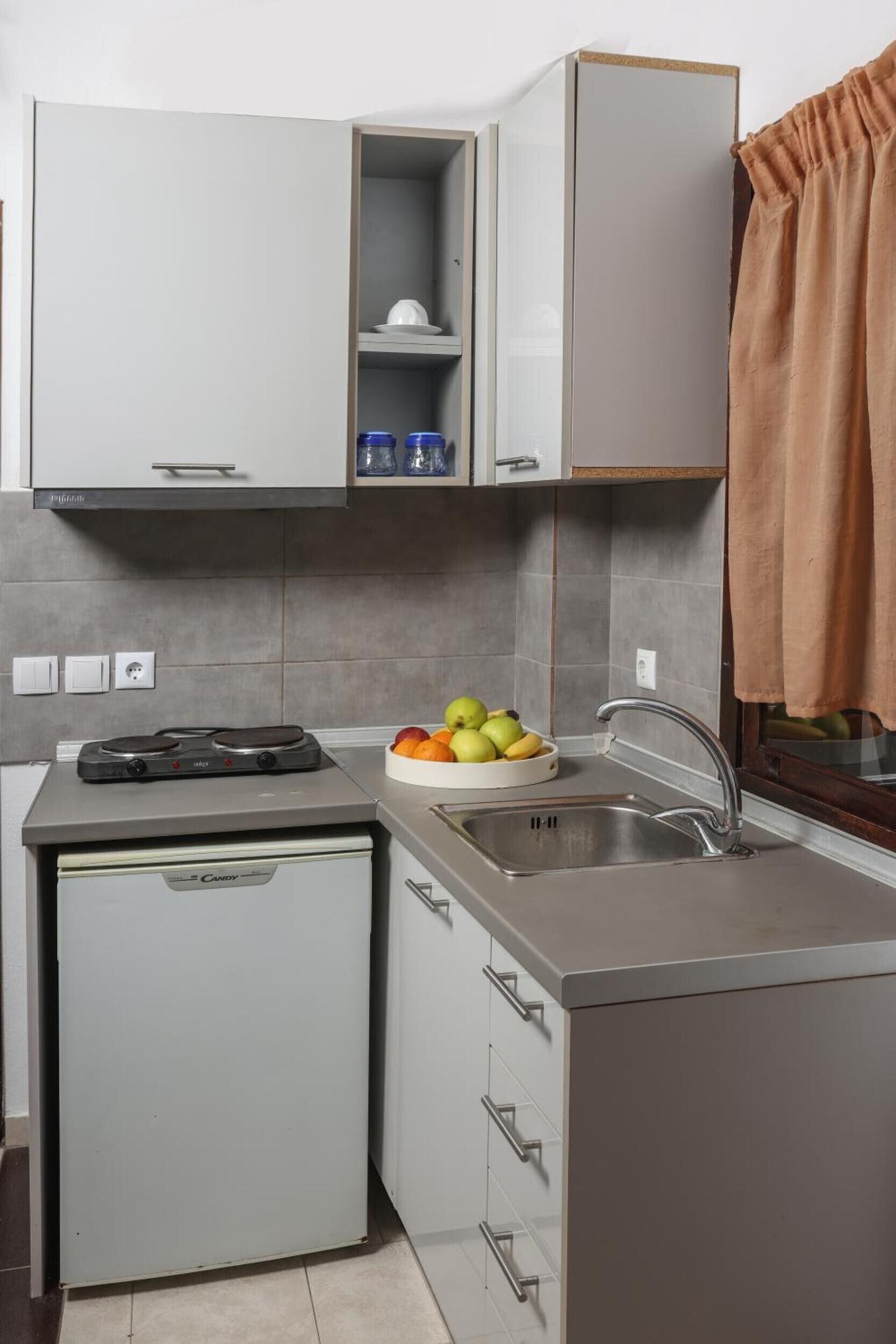 Een koelkast, een kookplaat, een waterkoker, kookgerei, borden en bestek