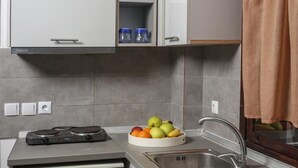 Una cuina compacta amb rentaplats integrat, un rentamànega i un plat de fruita a la tauleta.