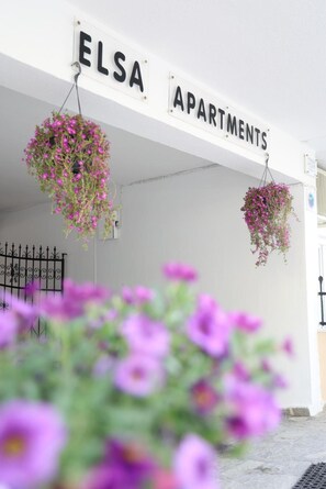 Een gevel met een bord waarop 'ELSA APARTMENTS' staat en bloembakken.