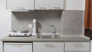 Moderni keittiö, jossa on valkoiset kaapit, sisäänrakennettu astianpesukone ja työtaso, jossa on paikka tehosekoittimelle.