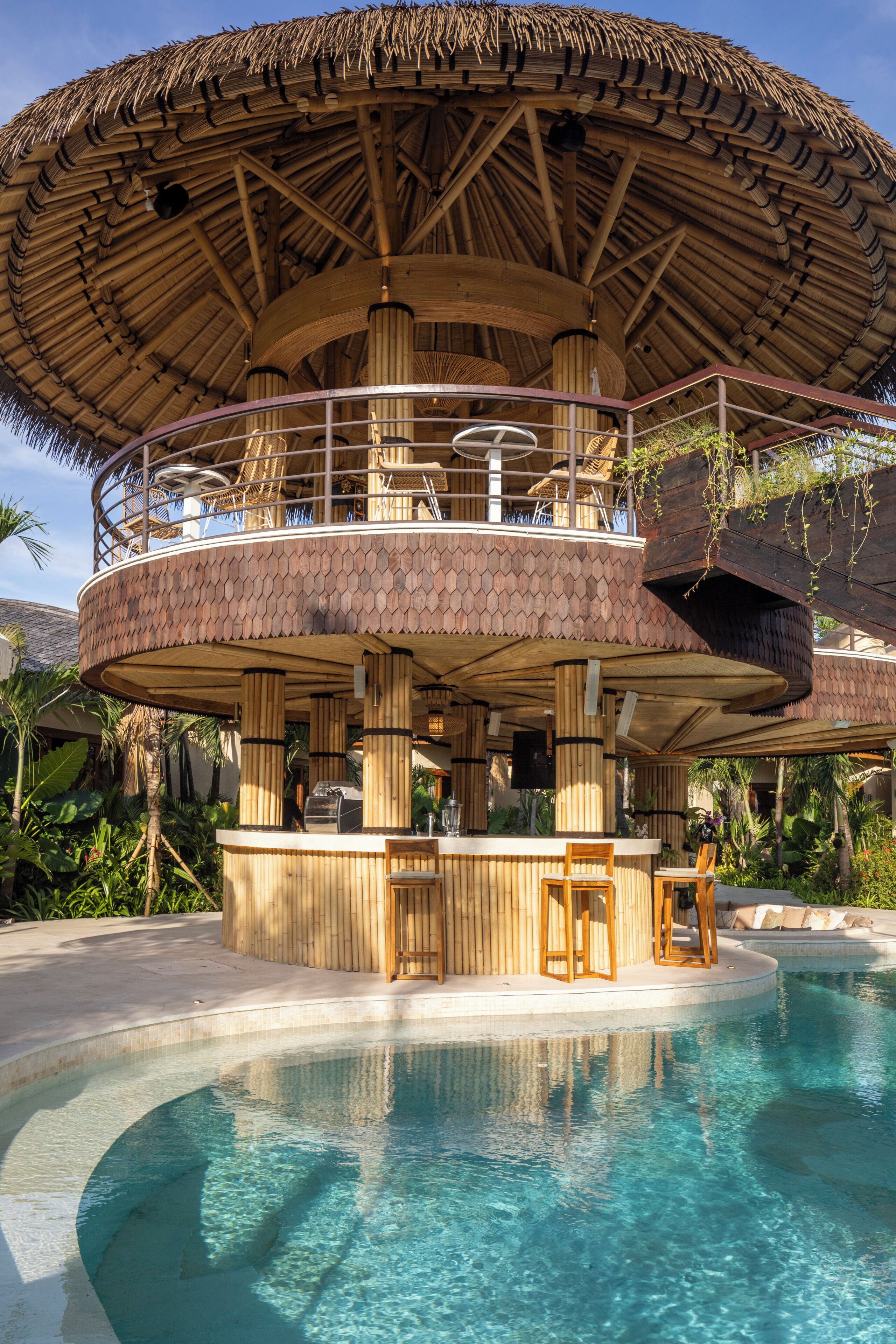 A circular wooden structure with a thatched roof, a pool, and a bar area.