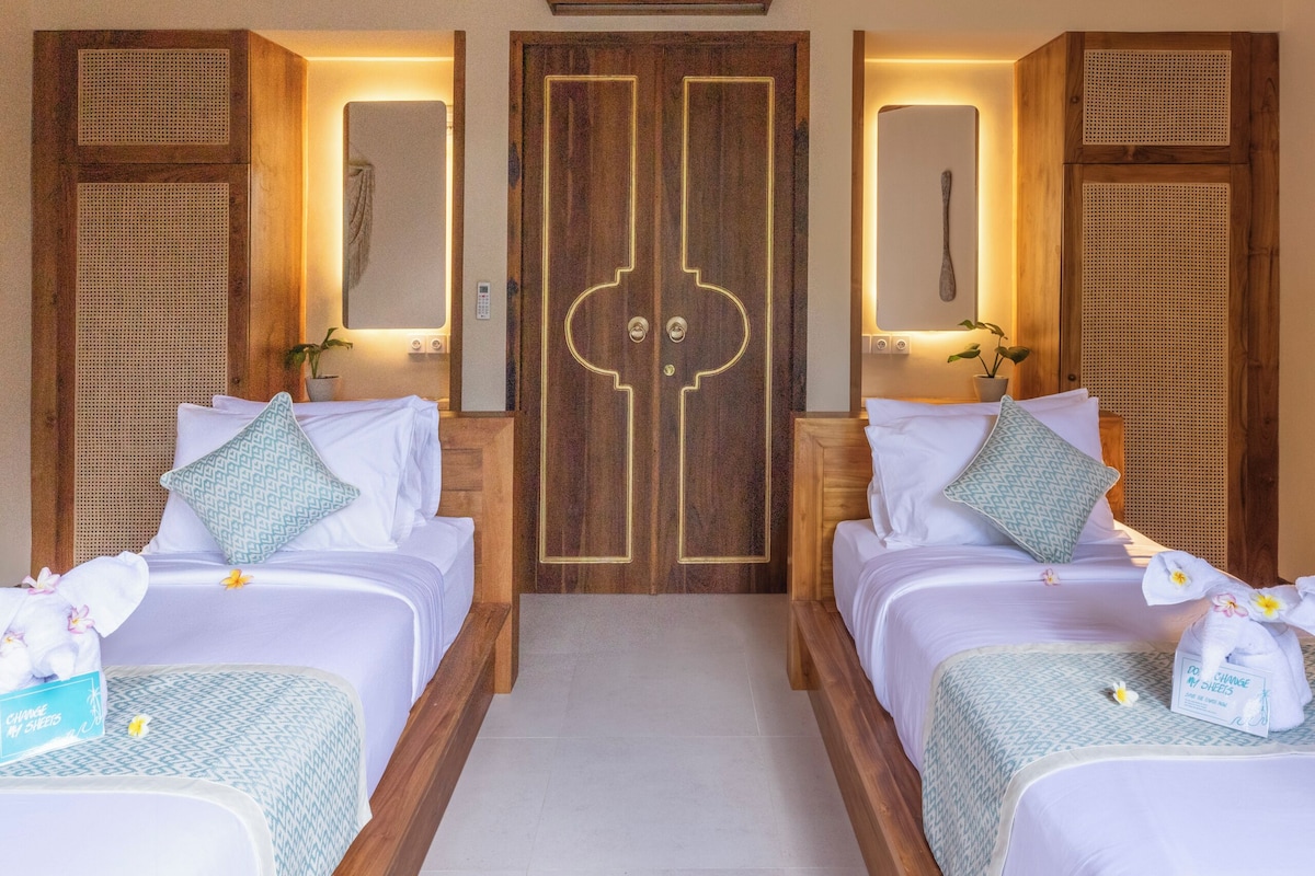 A hotel room with two beds, wooden headboards, a large mirror, and a wooden ceiling.