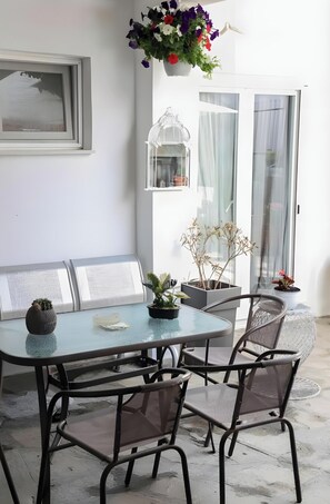 En matplats med ett bord, stolar, en bänk, krukväxter och en fågelbur.