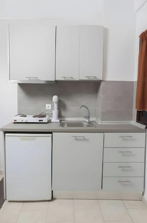 Eine moderne Küche mit weißen Schränken, einer Edelstahl-Spüle, einem integrierten Geschirrspüler und einer Arbeitsplatte mit Wasserkocher.
