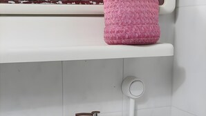 Un bagno con un lavandino bianco, un dispenser per sapone rosa e un water bianco.