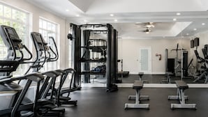 A gym with treadmills, weight benches, and a squat rack. - Elite Cozy Suites Buford (Buford)