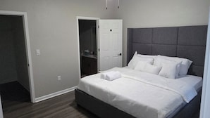 A bedroom with a bed, a ceiling fan, a door, and a closet. - Elite Cozy Suites Buford (Buford)
