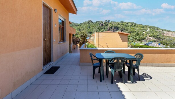 A terrace with a table and chairs, a door, and a view of a hilly landscape. - Terrace With sea View, Parking Space, air Conditioning (Castelsardo)