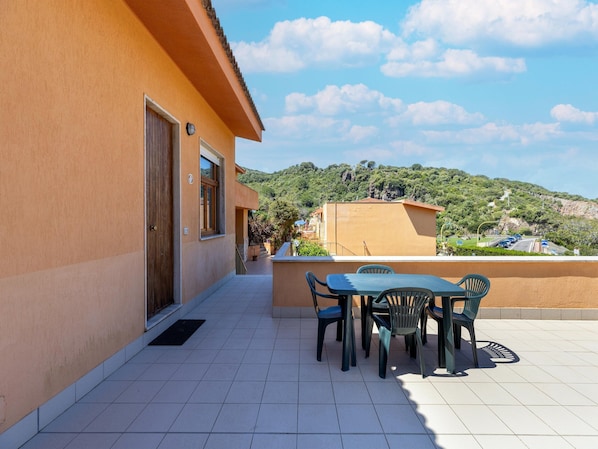 A terrace with a table and chairs, a door, and a view of a hilly landscape. - Terrace With sea View, Parking Space, air Conditioning (Castelsardo)
