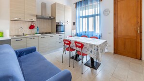 A modern kitchen with a dining area, including a sofa, chairs, and a table. - Terrace With sea View, Parking Space, air Conditioning (Castelsardo)