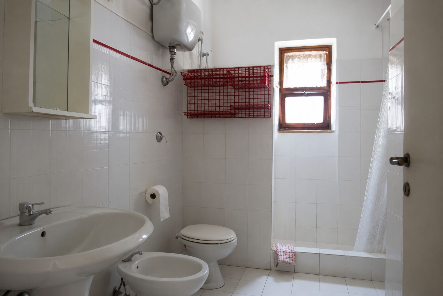 A bathroom with a sink, bidet, toilet, and shower.