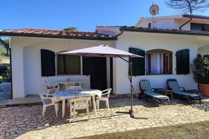 A building with a tiled roof, a patio with a table and chairs, and two lounge chairs. - Detached house 50 meters from the sea, ideal for an all-round relaxing vacation. (Giannella)