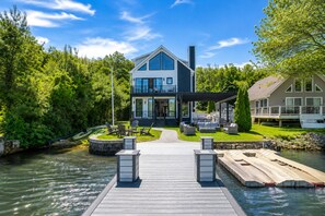 Ein modernes Haus mit Anlegesteg, Sitzgelegenheit im Freien und einem Fluss.
