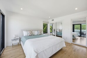 Ein geräumiges Schlafzimmer mit einem großen Bett, einem Nachttisch und Blick auf den Balkon.