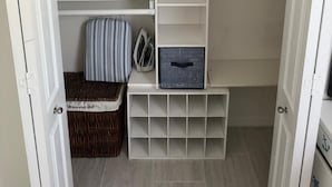 Un armario vestidor con estantes abiertos, espacio para colgar ropa y un mueble de almacenamiento.