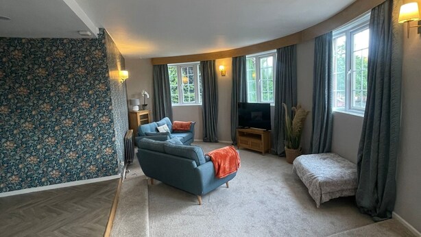 A spacious living room with a sofa, a TV, and a small table. - Carnegie Library Christie apartment (Swinton)