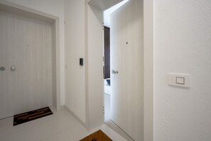 A hallway with white walls, a door with a doormat, and a light switch. - Dimora Venere - Modern Urban Retreat in the Heart of Bari (Bari)