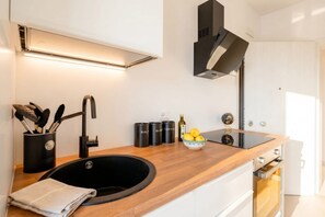 Eine moderne Küche mit einer Holzausziehtafel, einem schwarzen Spülbecken und Edelstahlgeräten.