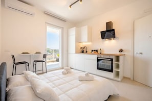 A modern bedroom with a bed, a small kitchenette, and a dining area with chairs. - Dimora Venere - Modern Urban Retreat in the Heart of Bari (Bari)