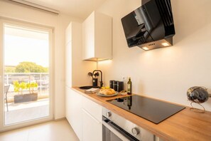 Eine moderne Küche mit Flachbildfernseher, einer Holzarbeitsplatte und Blick durch eine Schiebetür in einen Außenbereich.