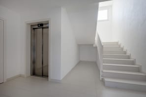 A modern interior with a white elevator, a staircase, and a plain wall. - Dimora Venere - Modern Urban Retreat in the Heart of Bari (Bari)