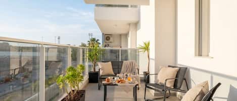 A balcony with a table set for breakfast, two chairs, and potted plants.