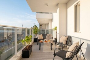 A balcony with a table set for breakfast, two chairs, and potted plants. - Dimora Venere - Modern Urban Retreat in the Heart of Bari (Bari)
