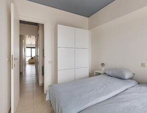 A bedroom with a bed, a wardrobe, and a nightstand. - Sea View Apartment for 6 in Zeedijk (Blankenberge)