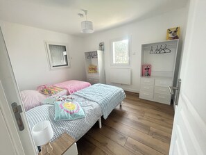 Un dormitorio con dos camas, un armario, un radiador y una ventana.