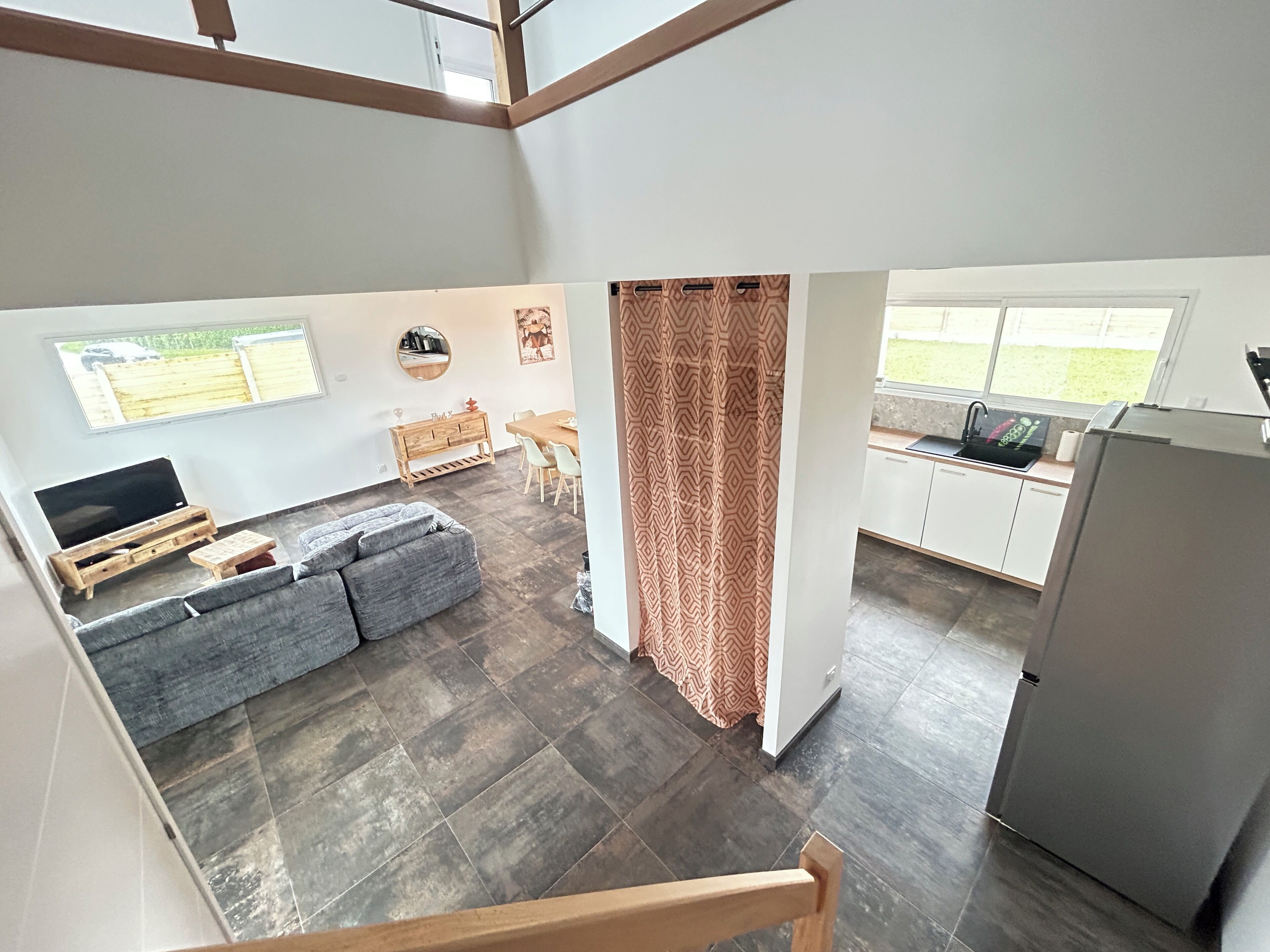 A modern interior with a sofa, dining table, kitchen area, and a TV.