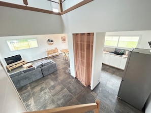 A modern interior with a sofa, dining table, kitchen area, and a TV.