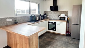 A modern kitchen with a wooden island, built-in oven, microwave, and stainless steel refrigerator. - New 6 person villa with enclosed garden in Ambleteuse (ambleteuse)