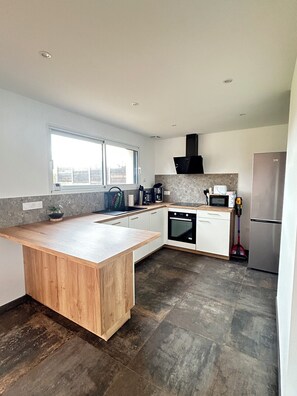 A modern kitchen with a wooden island, built-in oven, microwave, and stainless steel refrigerator.