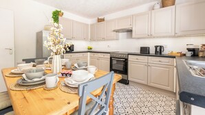 Una cocina moderna con armarios blancos, una mesa de comedor con platos y tazas, y un horno empotrado.