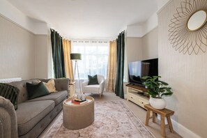 A living room with a sofa, a coffee table, a TV, a lamp, and a plant.