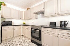 A kitchen with white cabinets, a black stove, and a microwave. - Beautiful 4 Bed House, Short Walk to Southampton General Hospital, Free parking (Southampton)