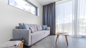 Un soggiorno moderno con un divano grigio, un piccolo tavolino in legno e un cesto in vimini.