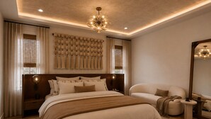Quarto com cama grande, sofá, mesa redonda e luminária pendente.