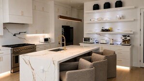 Cozinha moderna com ilha central, eletrodomésticos embutidos e área de estar.