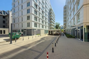 A modern building with multiple floors, a covered walkway, and a green dumpster. - Modern Studio in the City Centre | Close to the High Street (Wrocław)