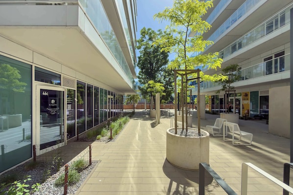 A modern building with glass facades, a central planter with a tree, and outdoor seating. - Modern Studio in the City Centre | Close to the High Street (Wrocław)