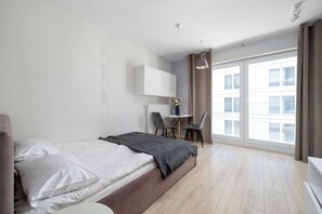 A modern hotel room with a bed, a desk, and a large window. - Modern Studio in the City Centre | Close to the High Street (Wrocław)