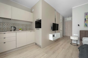 A modern kitchen with a tiled backsplash, a built-in oven, and a flat-screen TV. - Modern Studio in the City Centre | Close to the High Street (Wrocław)