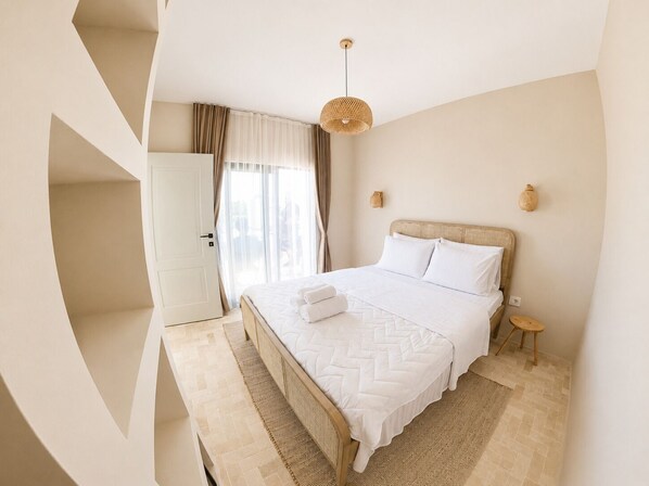 Een slaapkamer met een bed, nachtkastje, lamp, garderobe en raam met gordijnen.