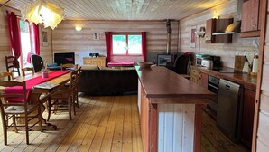 A cabin interior with a dining area, kitchen, and a large window. - Chalet in the Les Rousses resort, between Prémanon and LAMOURA (PREMANON)