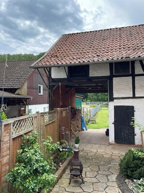 A traditional house with a tiled roof, a wooden fence, and a garden with a small tree and potted plants. - Kannemann vacation apartment (Herzberg am Harz)