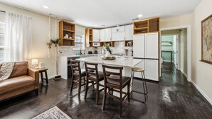 Una cocina moderna con una isla central, sillas de madera, un sofá y una mesa de comedor.