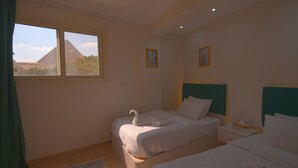 A bedroom with two beds, a window with a mountain view, and two framed pictures on the wall. - Pyramid-view retreat walk there in minutes (Cairo Governorate)